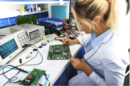 A woman working on an electronic board in a lab.